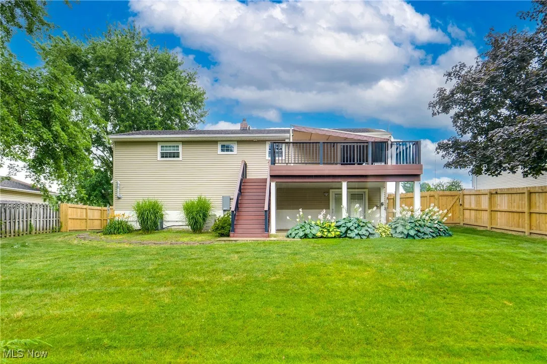 Rear view of house with stairway, a wooden deck, and a fenced backyard