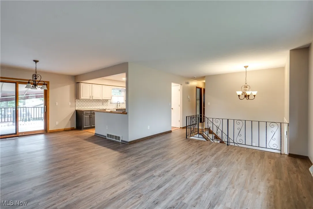 Unfurnished living room featuring a chandelier, wood finished floors, and healthy amount of natural light