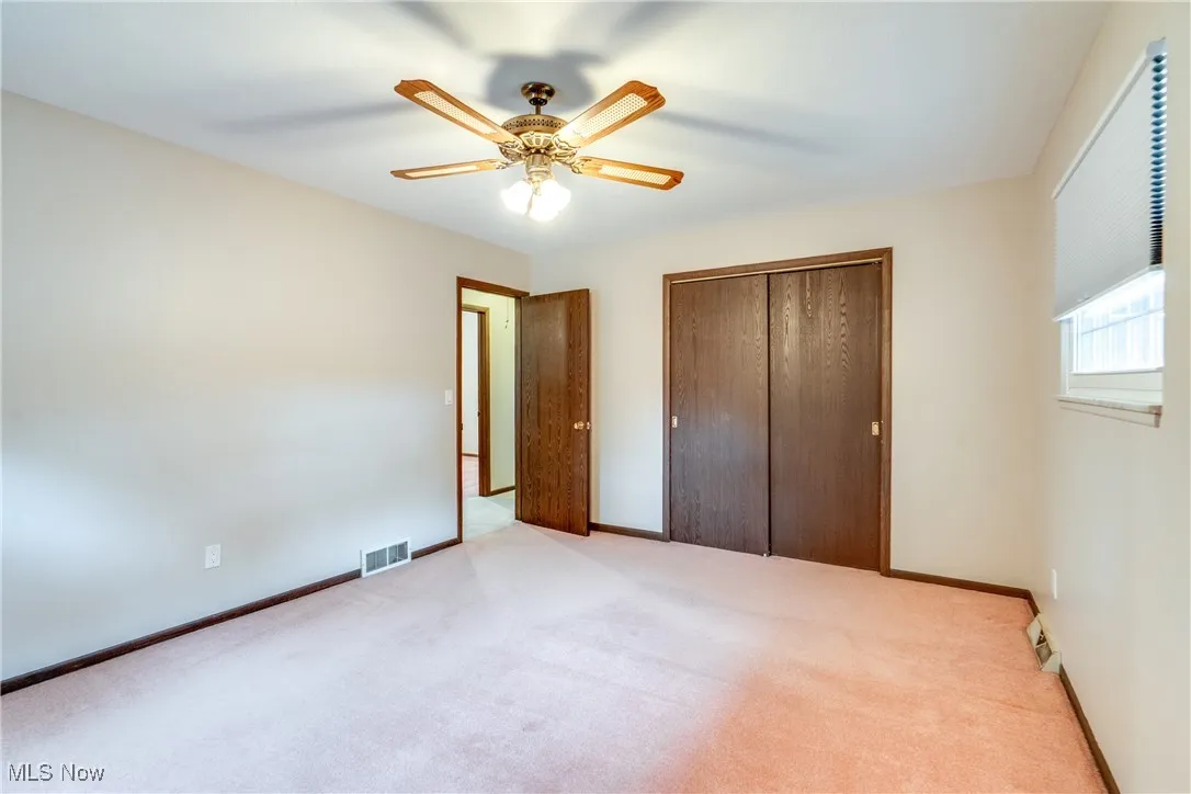 Unfurnished bedroom with a closet, light carpet, and a ceiling fan