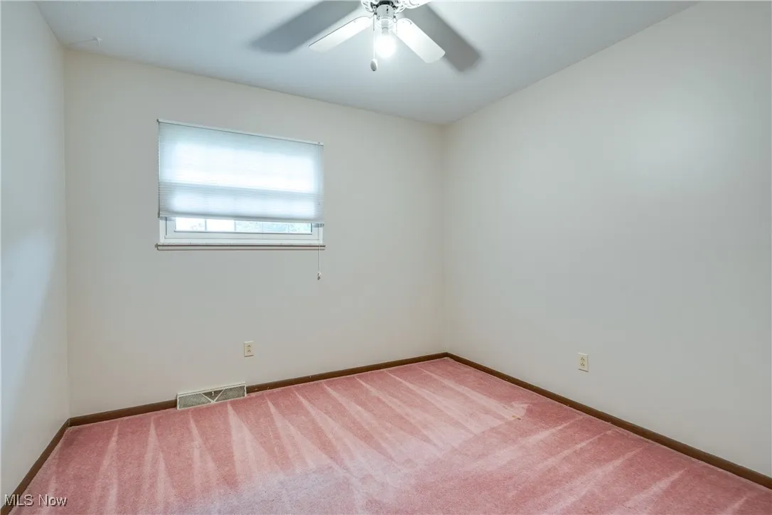 Carpeted empty room featuring baseboards and a ceiling fan