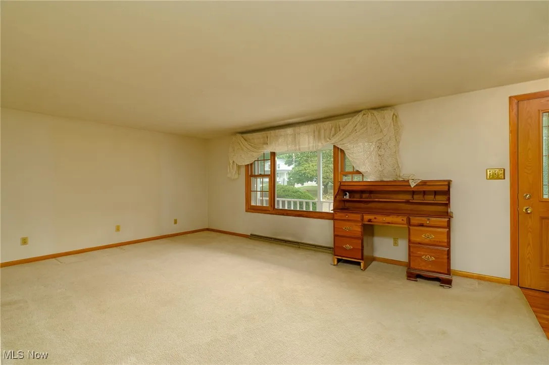 Living room bay window view of the front porch and hardwood floors underneath the carpet