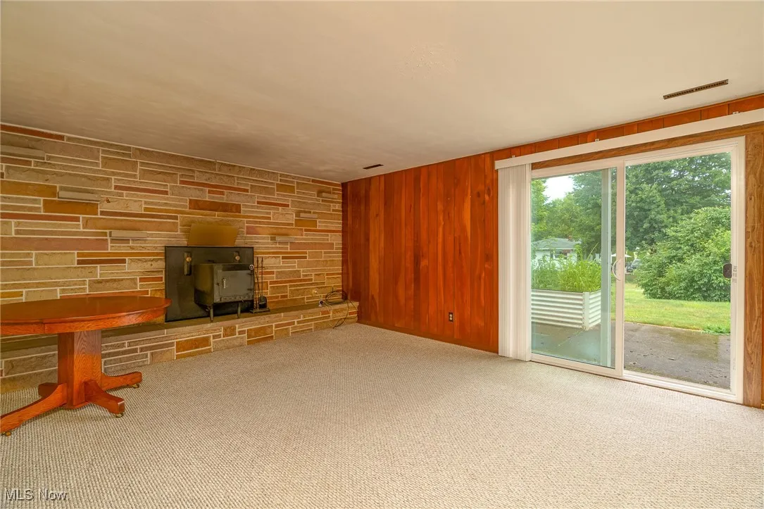 Family room stone wall and hearth with wood burner. Slider flows to outdoor patio and deck.
