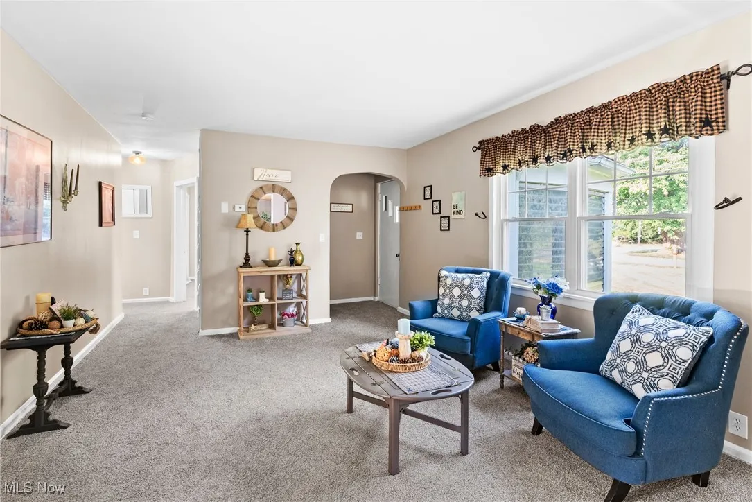 Carpeted living room with arched walkways and baseboards