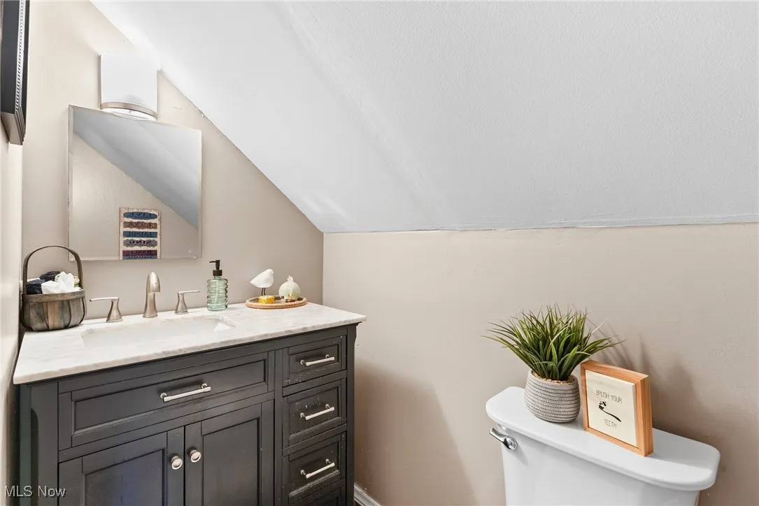 Half bath featuring lofted ceiling and vanity