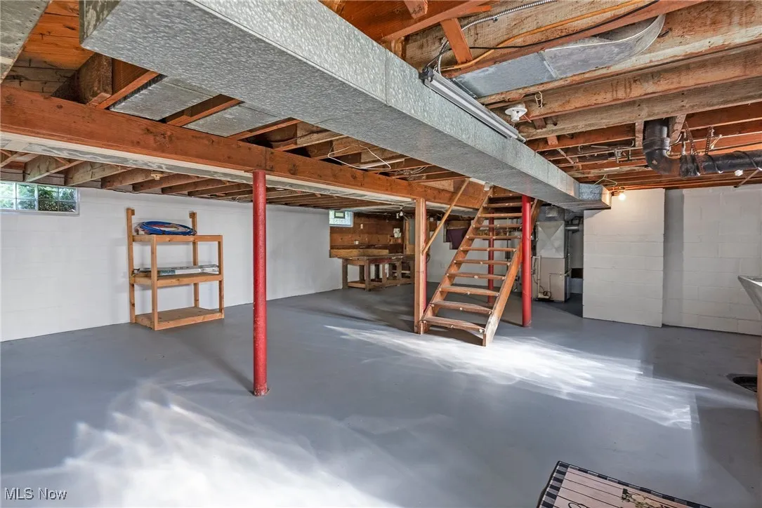 Basement featuring stairway, concrete block wall, and heating unit