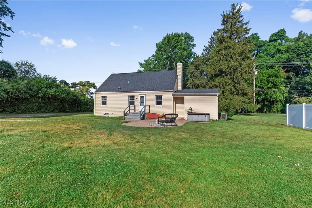 Back of house featuring a patio, a chimney, a yard, and entry steps