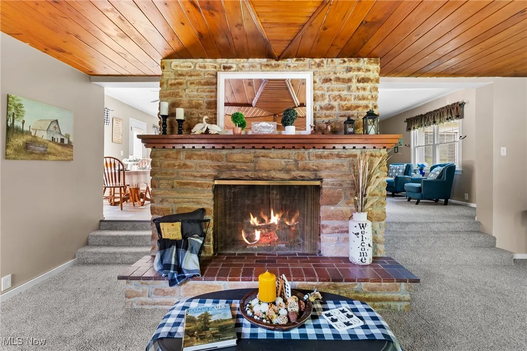 Living room with carpet flooring, wooden ceiling, a fireplace, and stairway