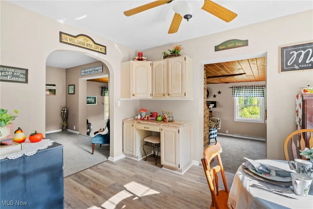 Dining room with arched walkways, a ceiling fan, wooden ceiling, light wood finished floors, and a baseboard radiator