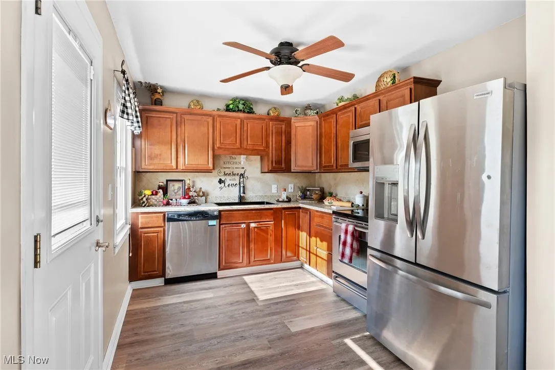 Kitchen with appliances with stainless steel finishes, light countertops, light wood-style flooring, and ceiling fan