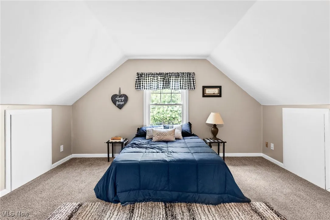 Bedroom featuring carpet and vaulted ceiling
