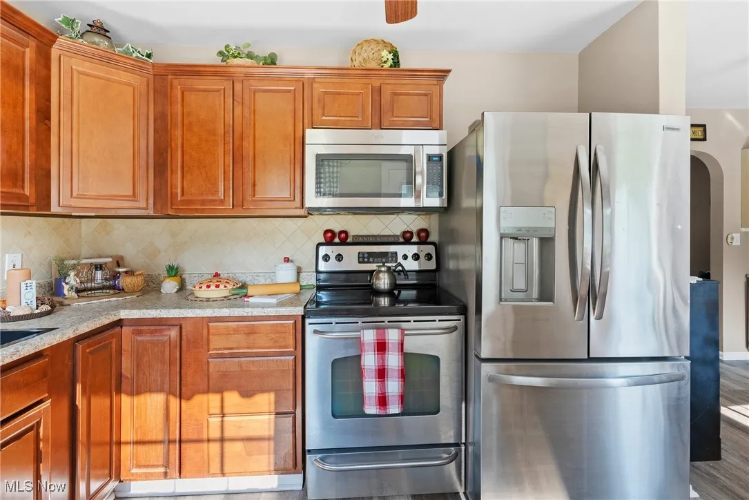 Kitchen featuring stainless steel appliances, decorative backsplash, and brown cabinets
