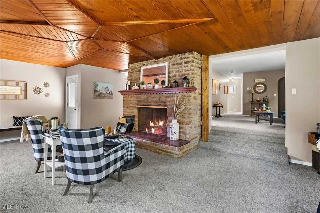 Living area with carpet flooring, wooden ceiling, and a fireplace