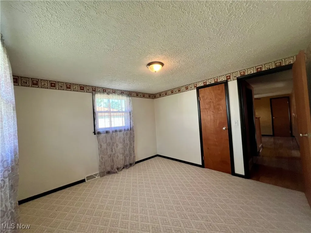Spare room featuring a textured ceiling and light colored carpet