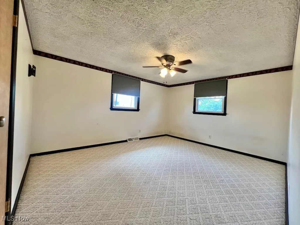 Bed room featuring plenty of natural light, ceiling fan, carpet, and a textured ceiling