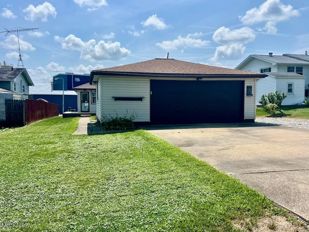 View of property exterior with roof with shingles, concrete driveway, and an attached garage