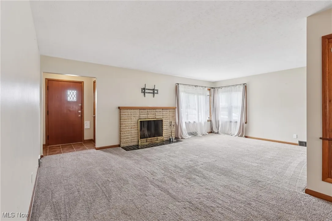 Unfurnished living room featuring plenty of natural light, carpet, and a fireplace