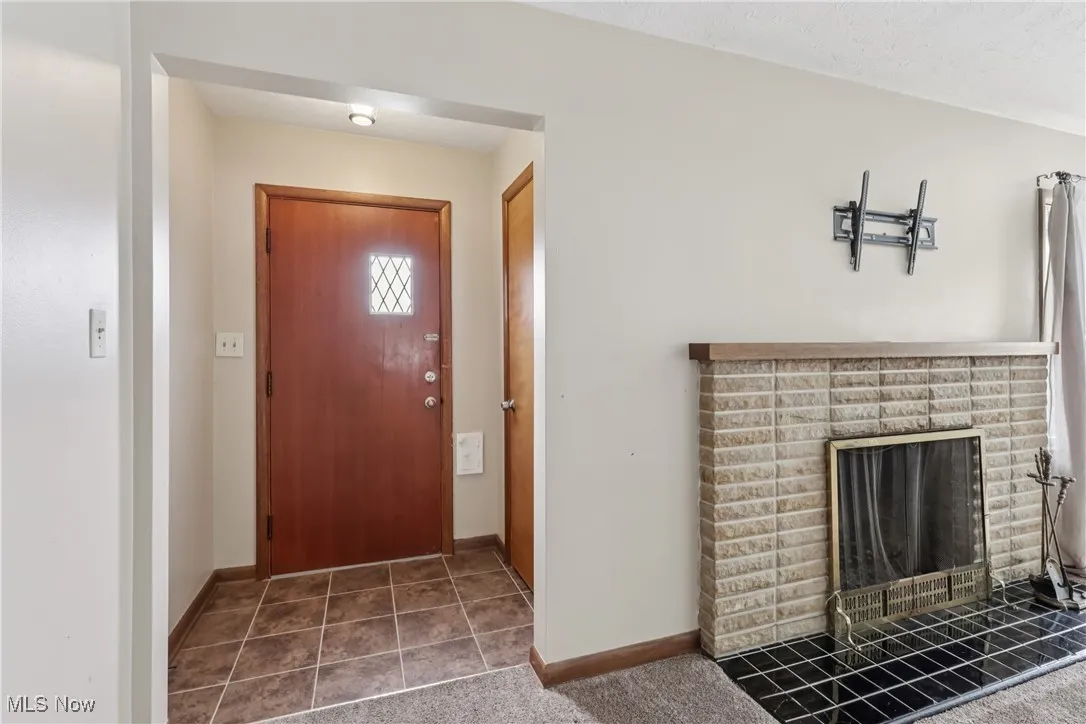 Entrance foyer with a brick fireplace and tile patterned flooring