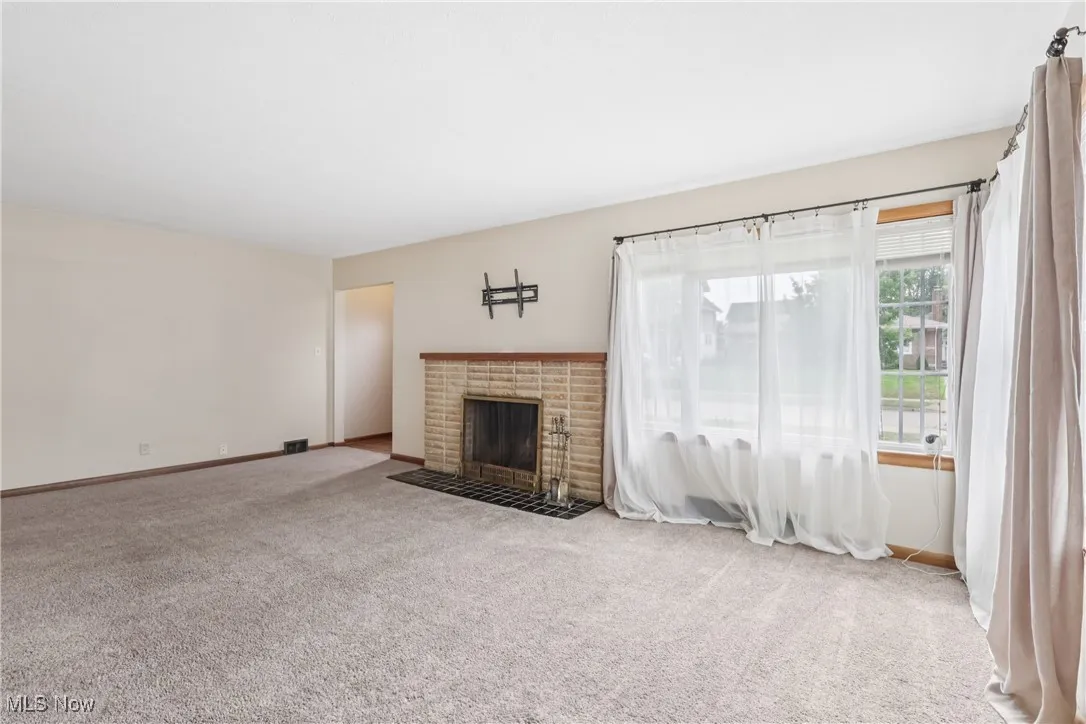 Unfurnished living room with carpet and a brick fireplace