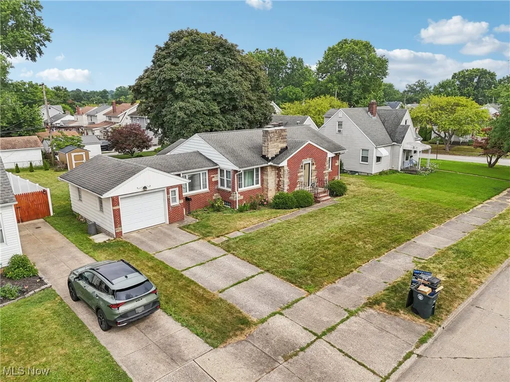 View of front of home with driveway, brick siding, a garage, a front lawn, and a chimney
