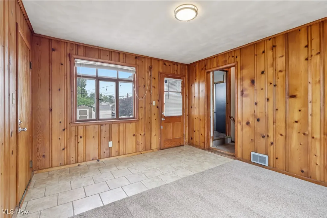 Empty room with wooden walls and light tile patterned floors