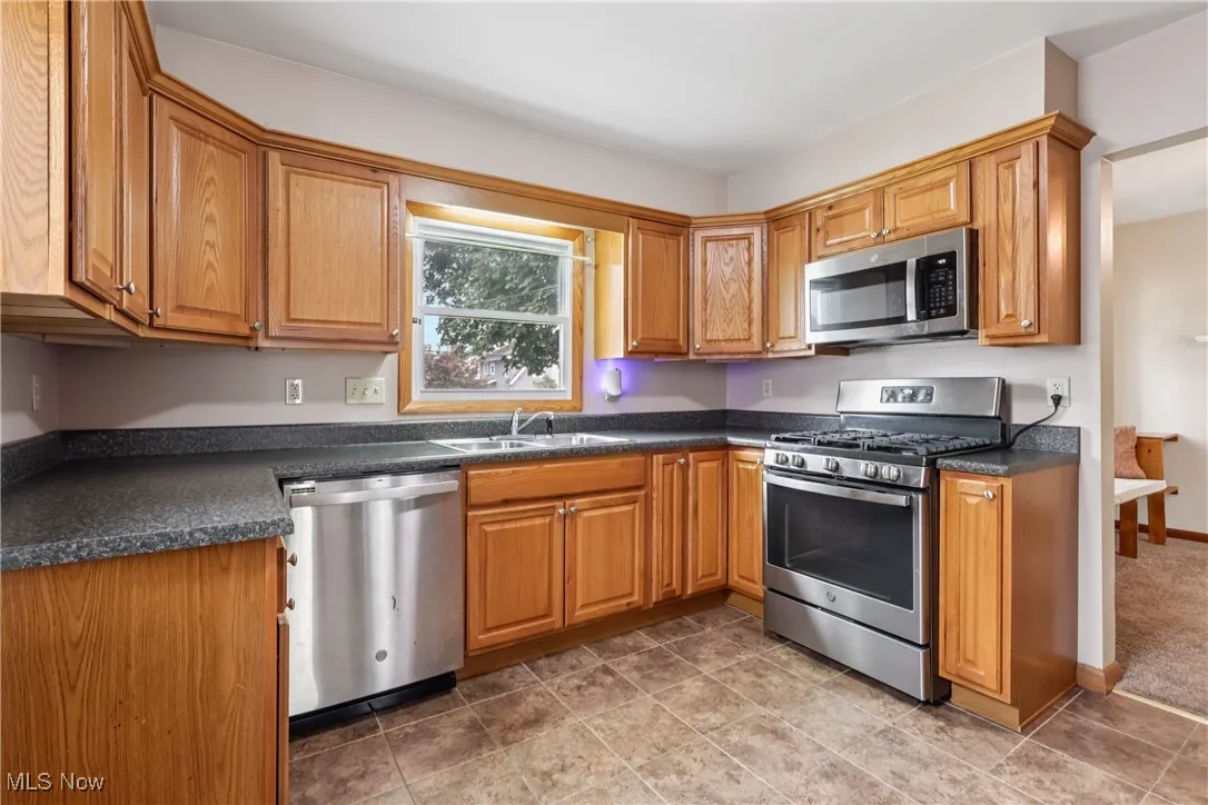 Kitchen featuring appliances with stainless steel finishes, dark countertops, and brown cabinets