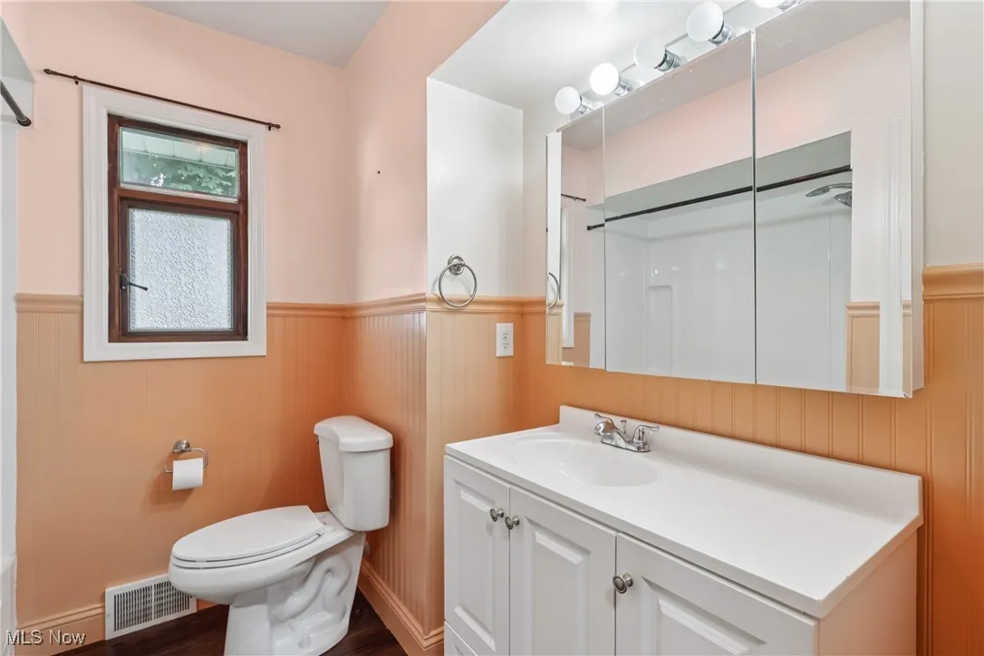 Full bathroom with wainscoting, a shower, vanity, and wood finished floors