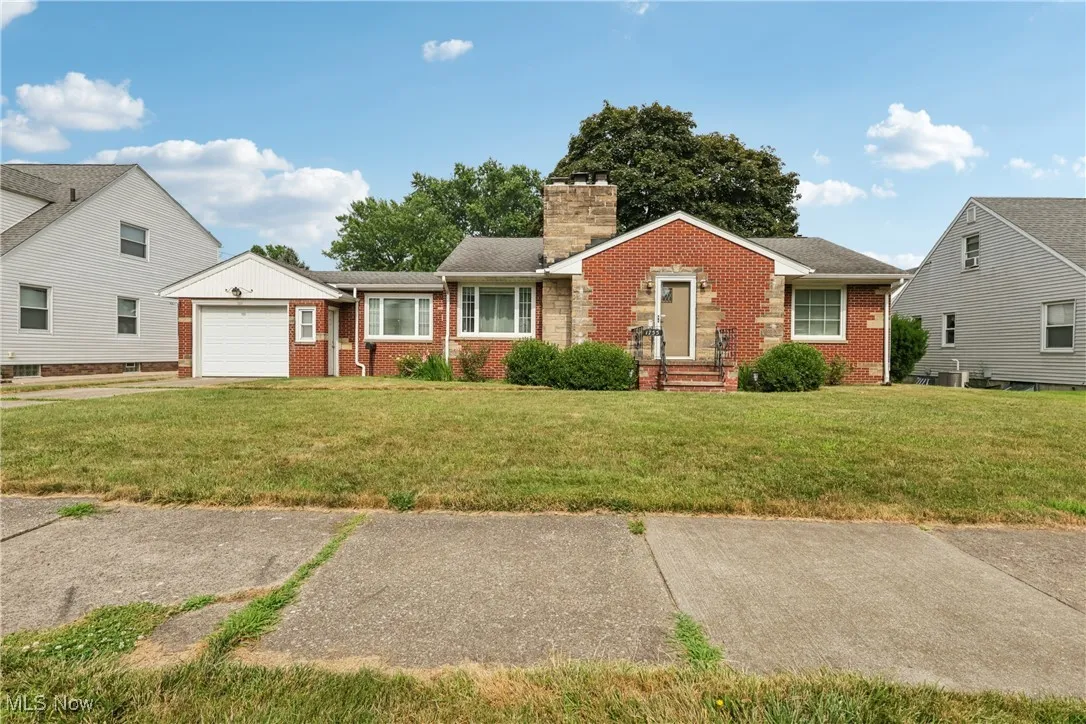 Ranch-style home with brick siding, a garage, a front yard, and a chimney
