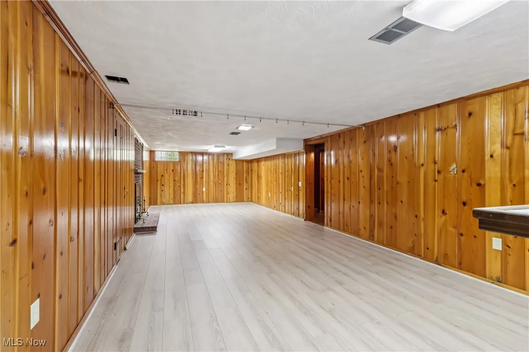 Basement featuring light wood finished floors and wooden walls