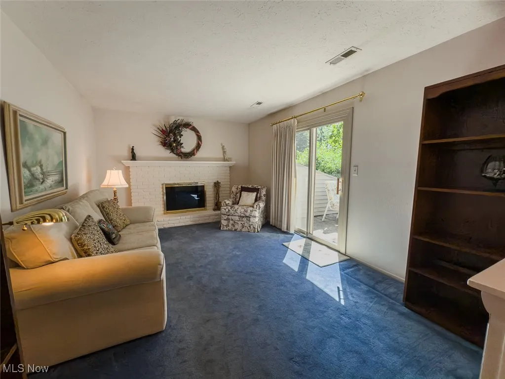 Family room with carpet, a brick wood burning fireplace and sliding glass doors leading out to private patio