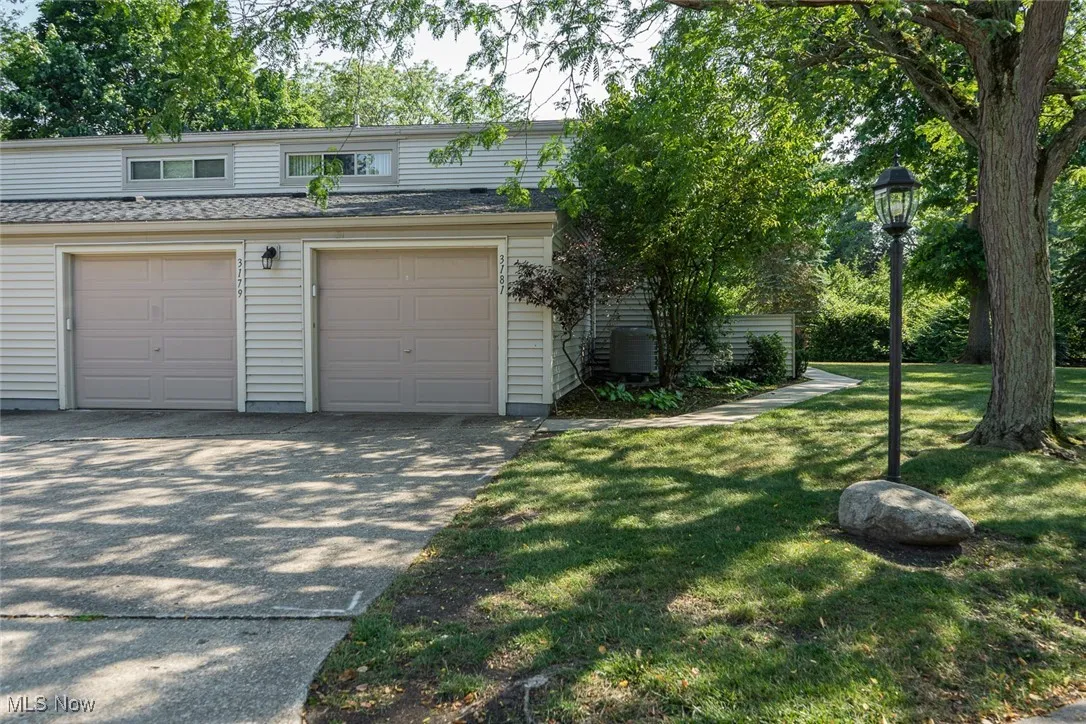 View of concrete driveway, a garage, and a shingled roof