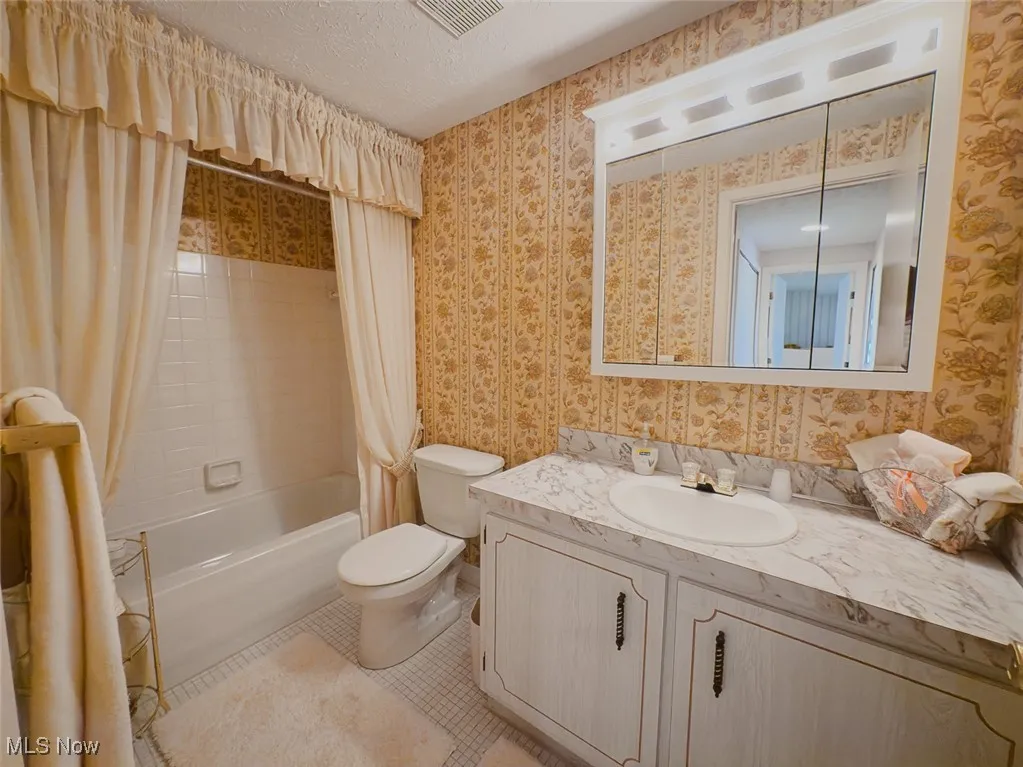 Bathroom with vanity, shower / tub combo with curtain, and tile patterned floors