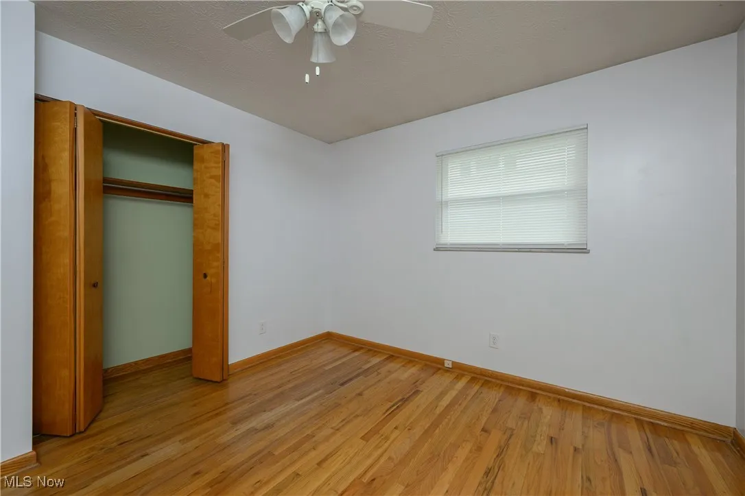 Unfurnished bedroom with light wood-style floors, a closet, and ceiling fan