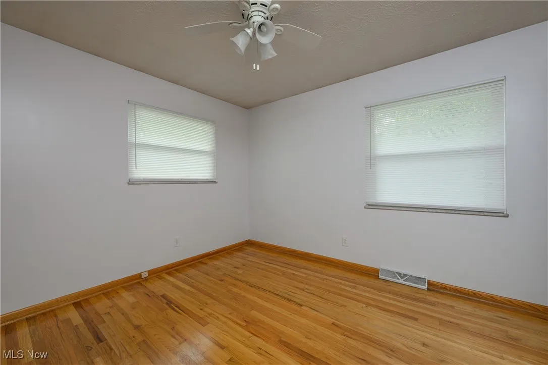 Empty room with light wood-style floors and ceiling fan