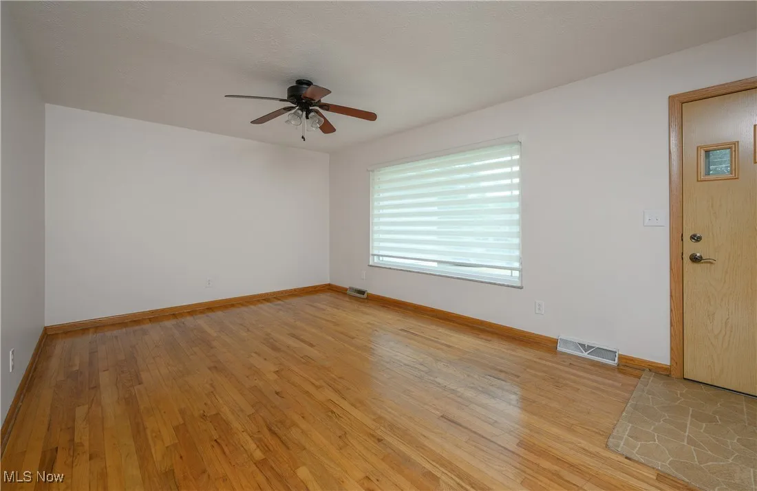 Unfurnished room with ceiling fan and light wood-style flooring