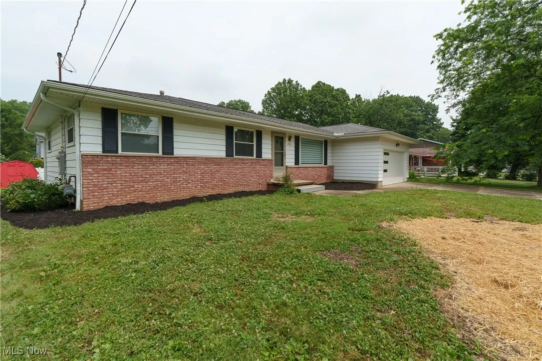 Ranch-style home with a garage, brick siding, concrete driveway, and a front yard
