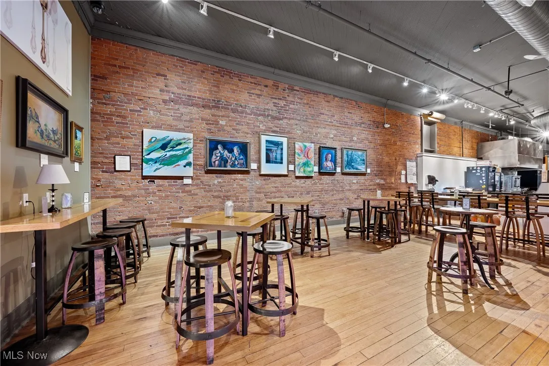 Dining space with brick wall, light wood-style flooring, and track lighting