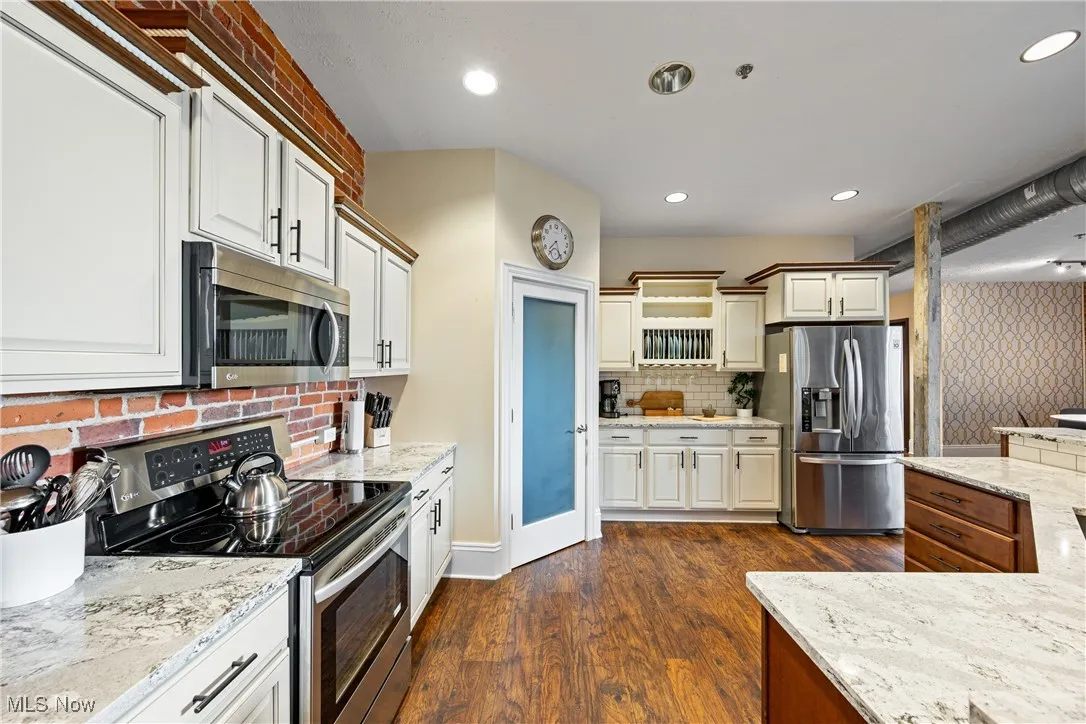Kitchen featuring stainless steel appliances, tasteful backsplash, light stone counters, and recessed lighting