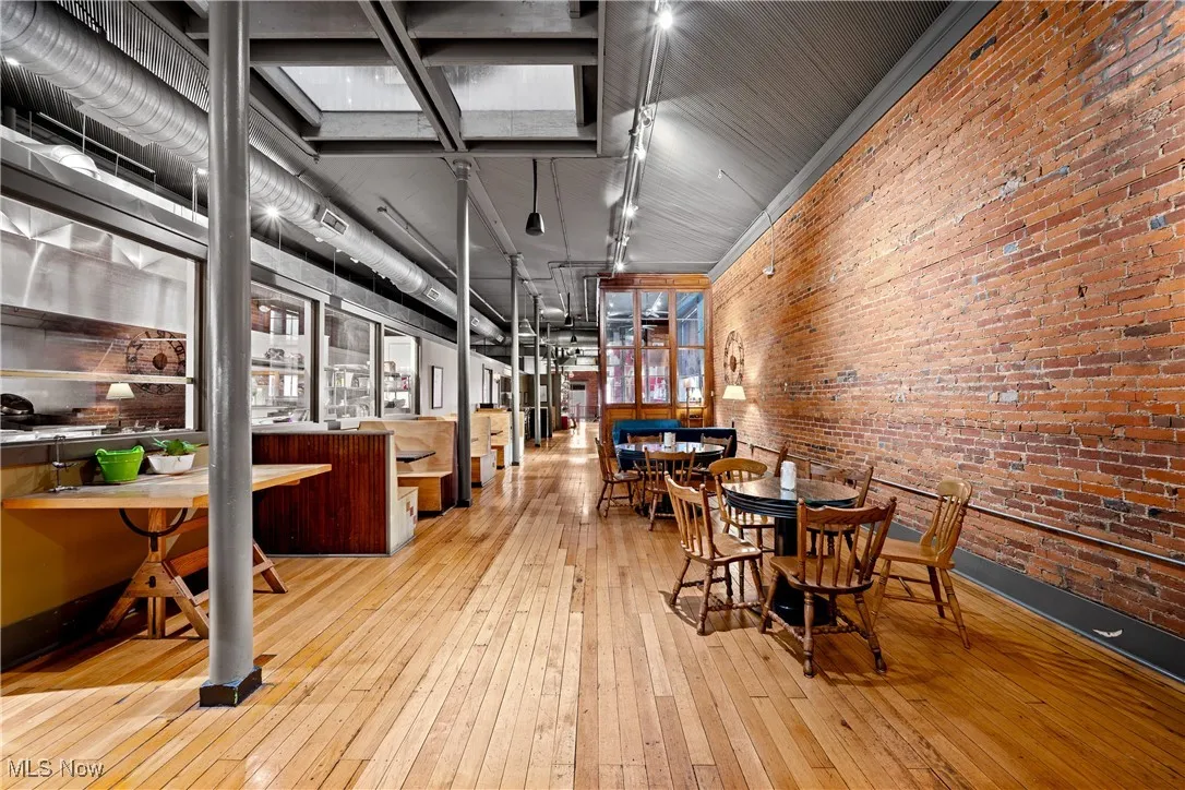 Dining area featuring brick wall and wood-type flooring