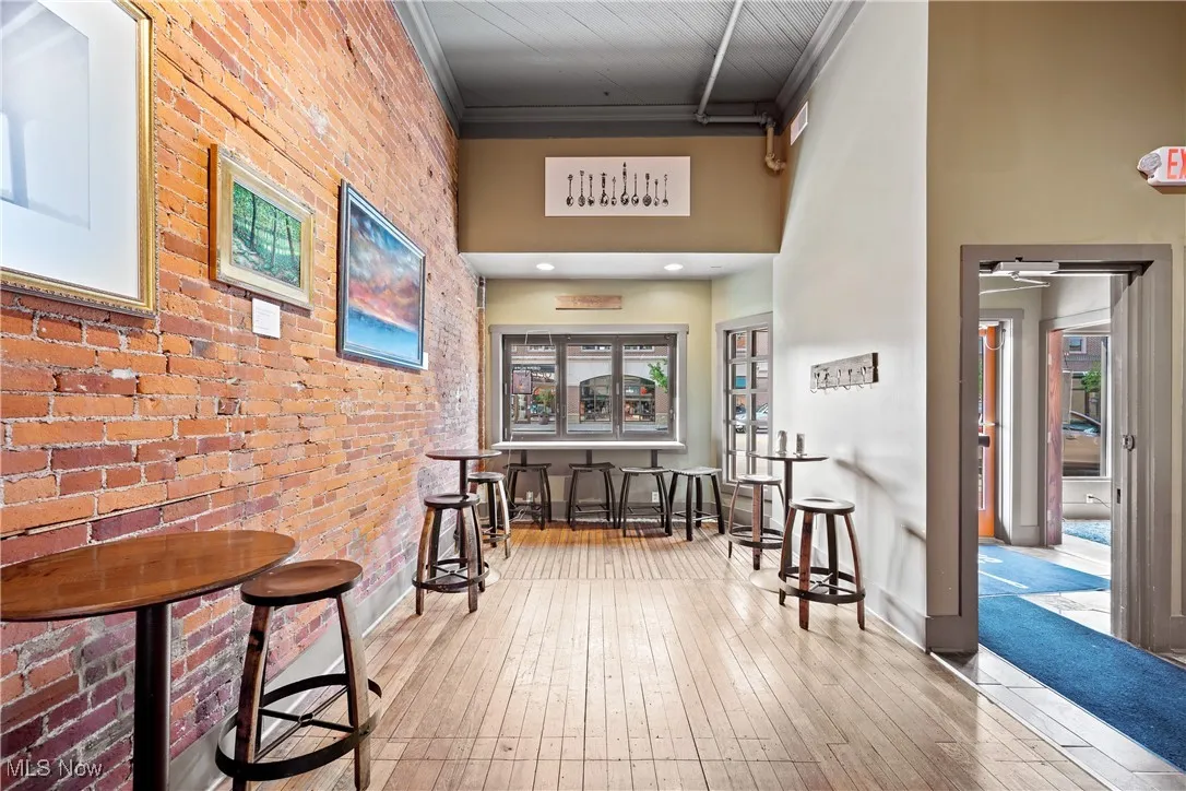 Hall featuring brick wall, hardwood / wood-style flooring, crown molding, and a high ceiling