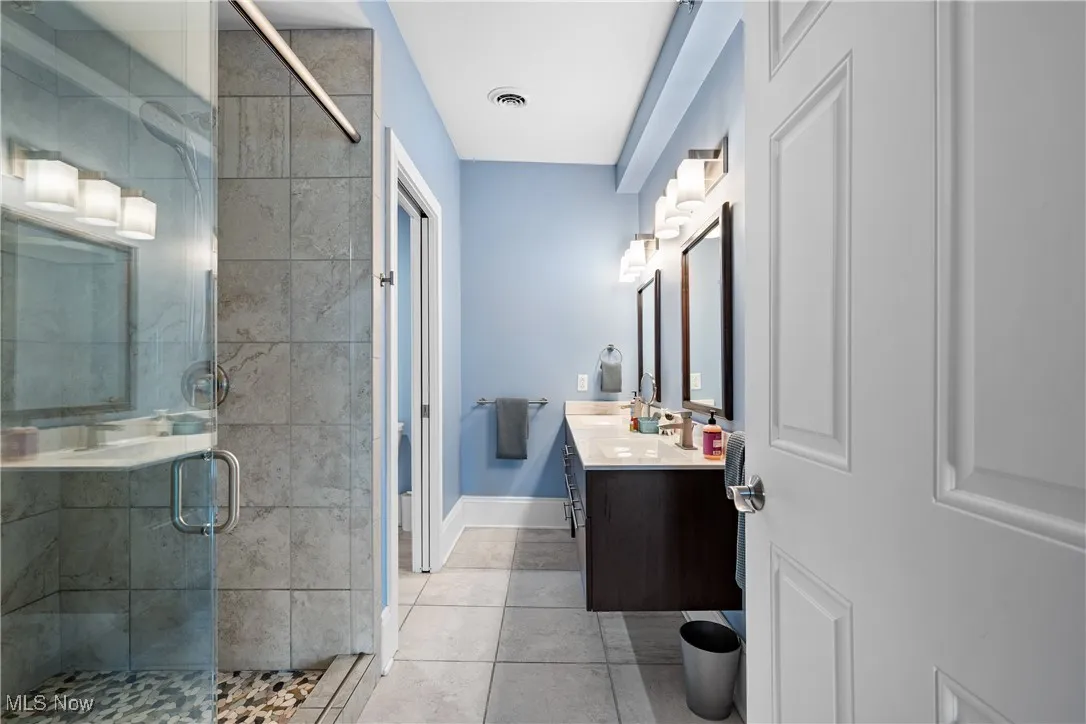 Bathroom featuring a stall shower, vanity, and tile patterned flooring