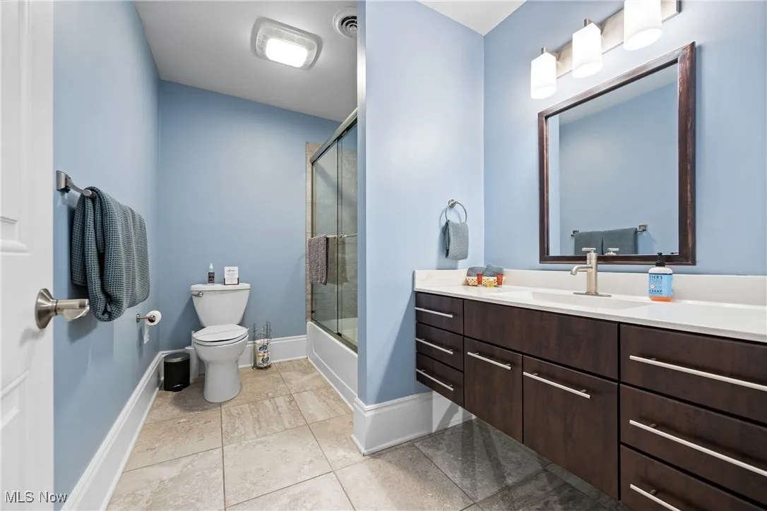 Bathroom featuring vanity and shower / bath combination with glass door
