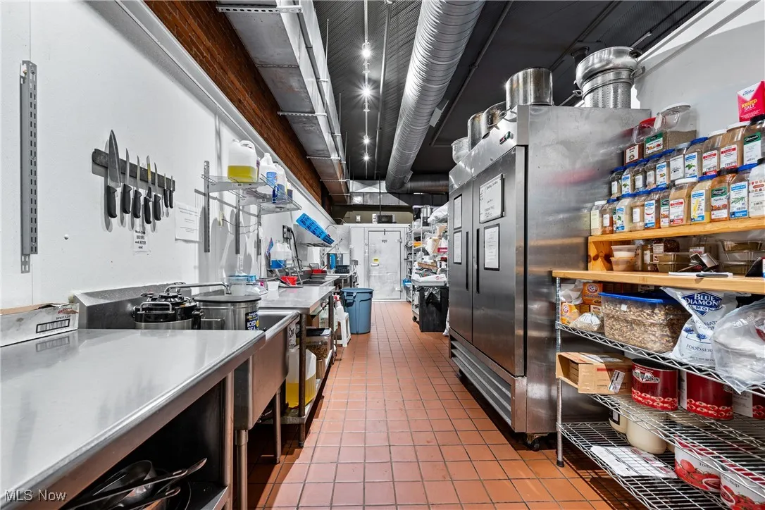 Kitchen with tile patterned flooring, stainless steel fridge, and stainless steel counters