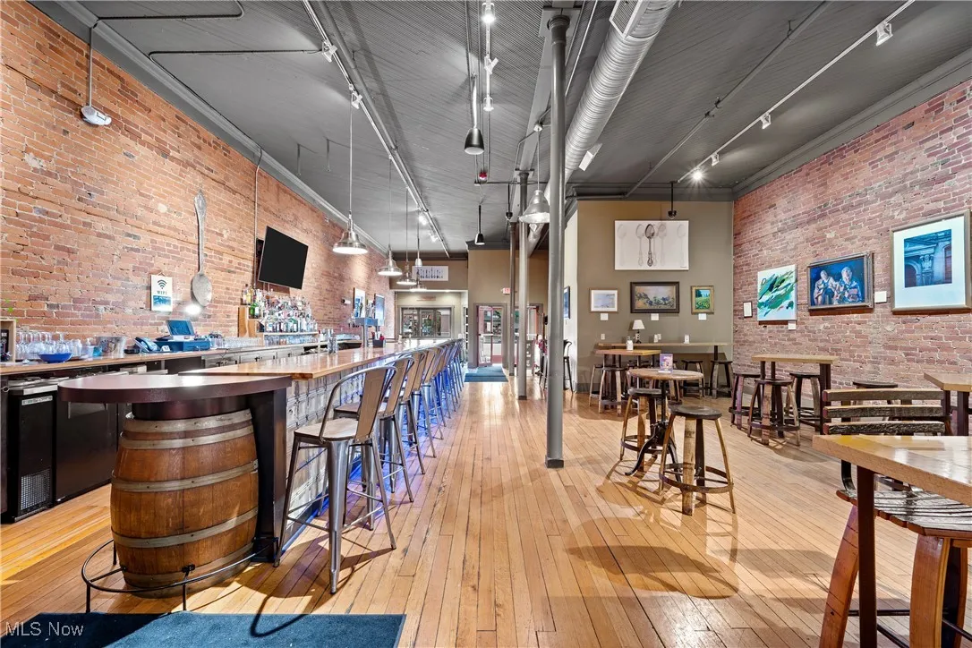 Community bar area with brick wall, track lighting, and light wood-type flooring