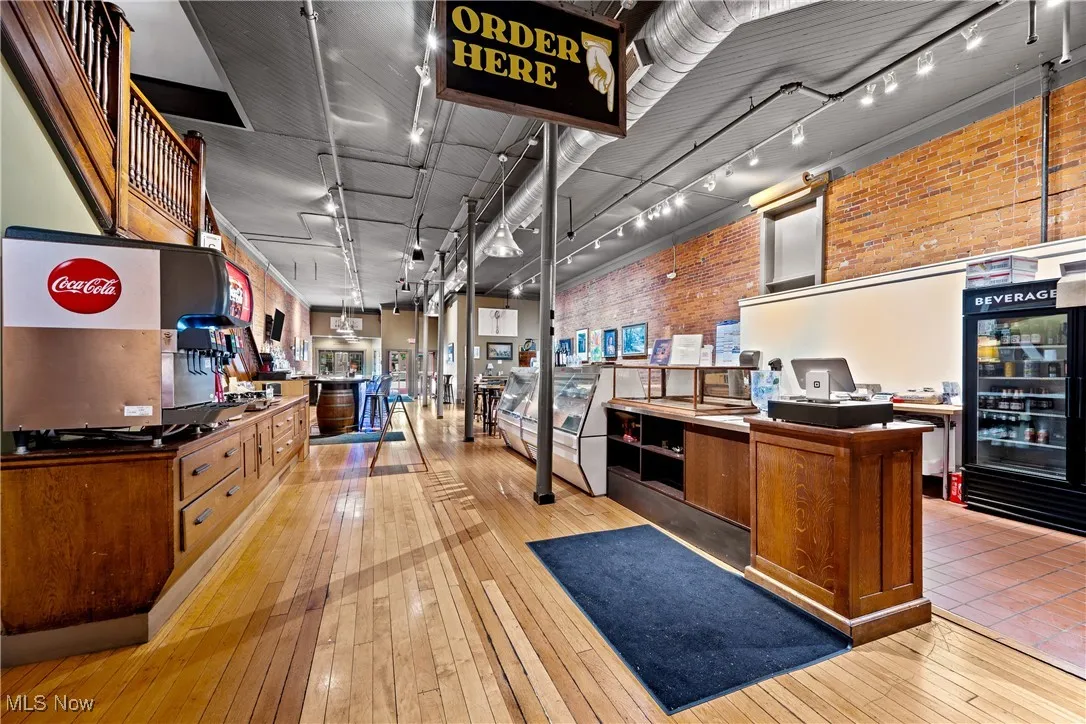 Kitchen with hardwood / wood-style flooring, brick wall, and track lighting