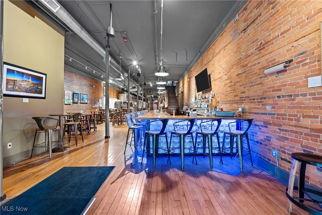 Community bar area with wood-type flooring and brick wall