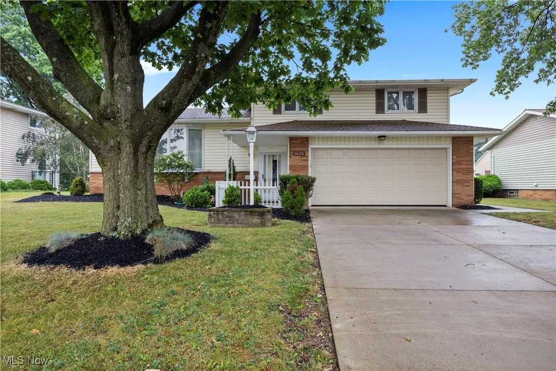 View of front of house with brick siding, a garage, driveway, and a front lawn