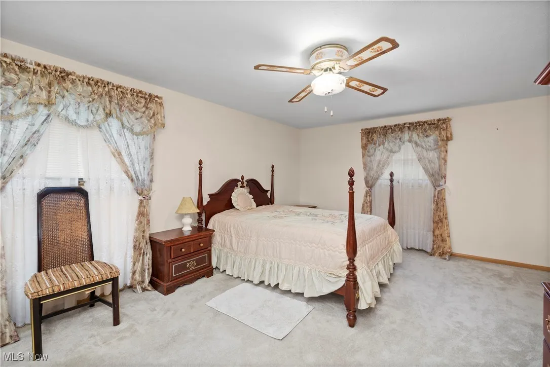 Bedroom featuring multiple windows, carpet flooring, and a ceiling fan