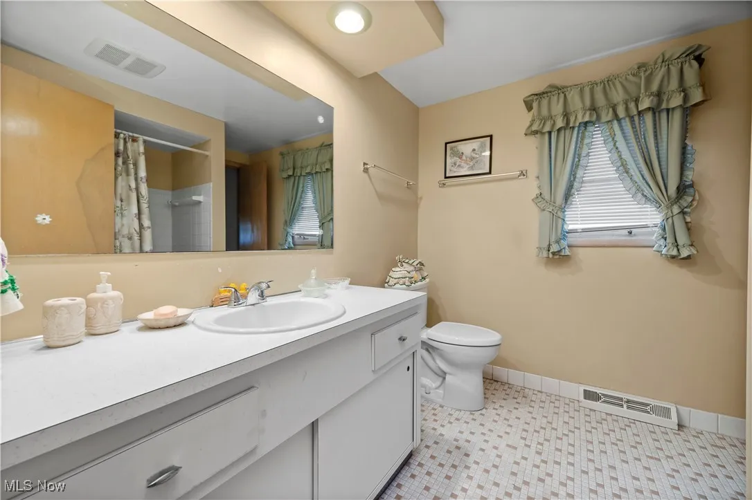 Full bathroom featuring vanity, curtained shower, and tile patterned floors