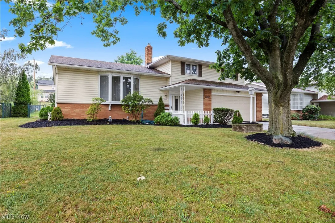 Split level home featuring brick siding, a chimney, and driveway