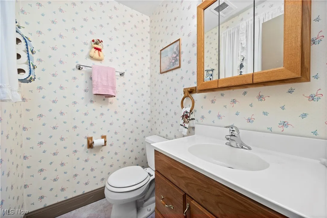 Bathroom featuring wallpapered walls and vanity
